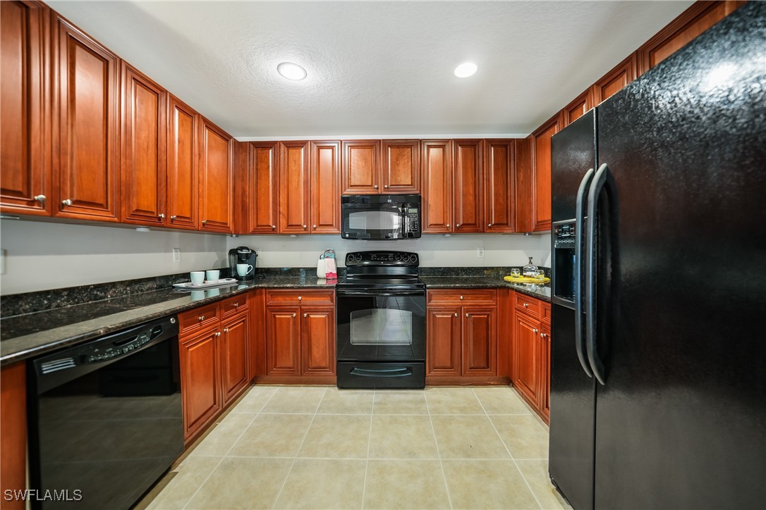 17084 Acapulco Road, Unit 211 Punta Gorda, FL 33955 - Photo 3 of 45 a kitchen with granite countertop stainless steel appliances and wooden cabinets