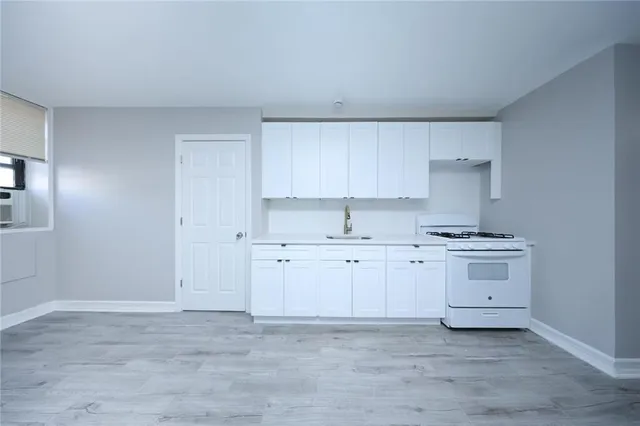 a kitchen with cabinets appliances a sink and a stove top oven