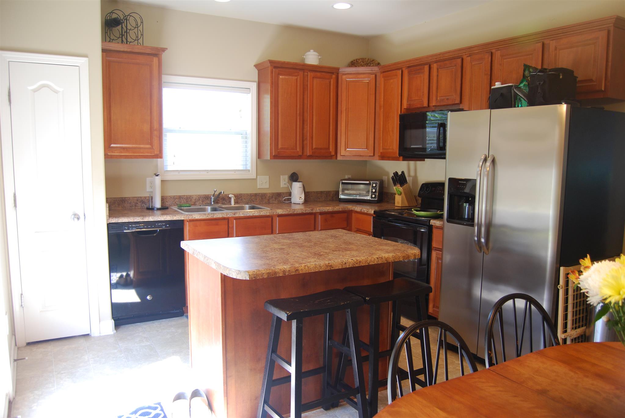 6003 Chickadee Circle Spring Hill, TN 37174 - Photo 9 of 23 a kitchen with stainless steel appliances kitchen island a table chairs sink refrigerator and microwave