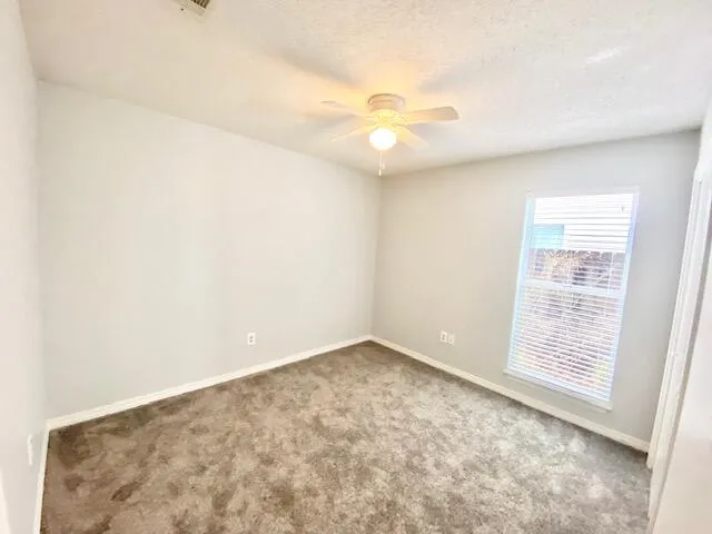 an empty room with windows and fan