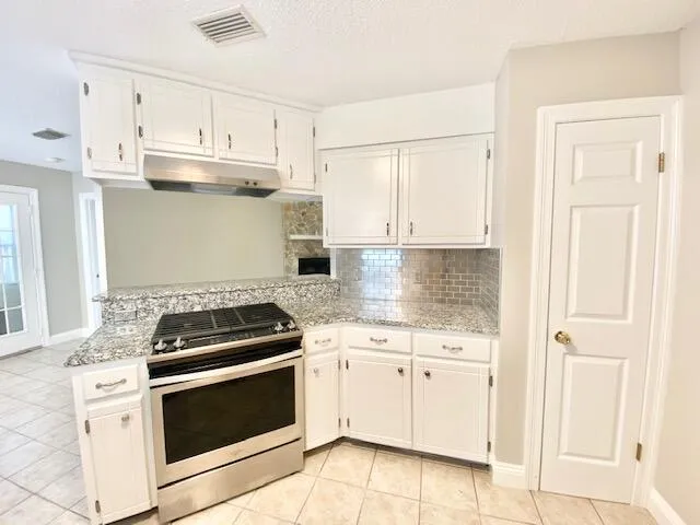 a kitchen with granite countertop white cabinets and white stove