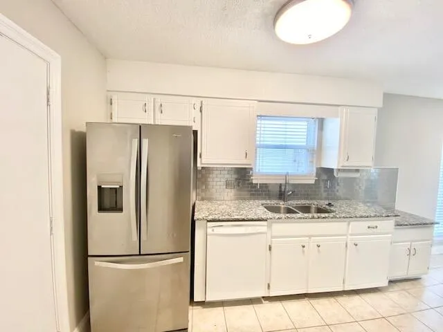 a kitchen with granite countertop a refrigerator sink stove and cabinets