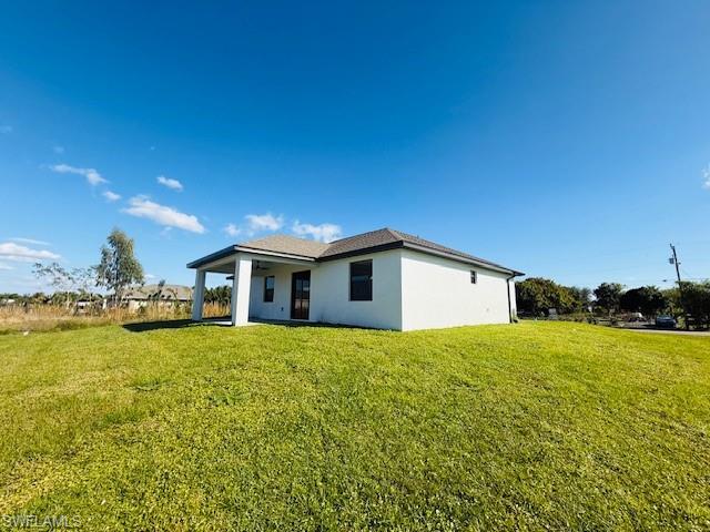 165 Patio Street Lehigh Acres, FL 33974 - Photo 8 of 34 Rear view of property with a lawn, stucco siding, and a patio