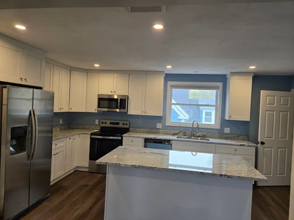 a large kitchen with granite countertop a stove a sink and a microwave
