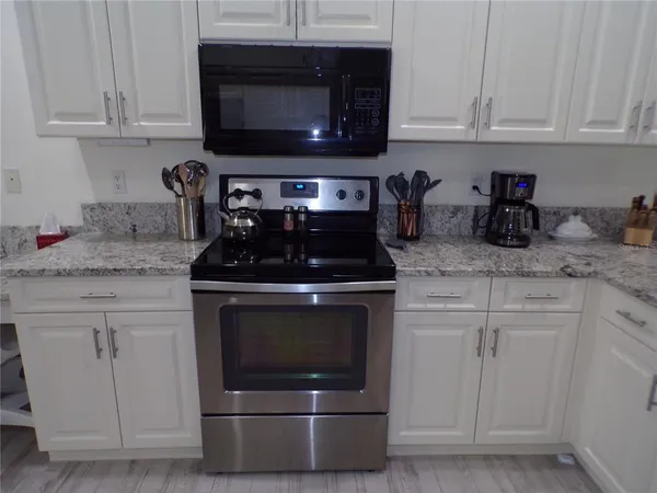 a kitchen with granite countertop white cabinets stainless steel appliances and a sink