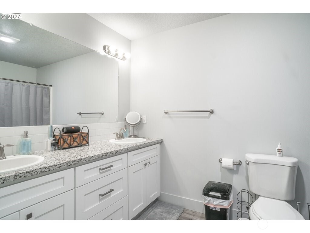 213 Oak Street Winlock, WA 98596 - Photo 25 of 32 a bathroom with a granite countertop sink a toilet and a mirror