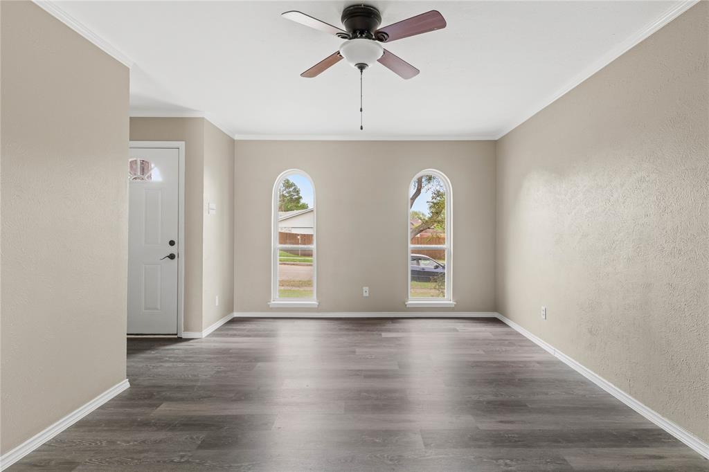 3109 Abbey Road Carrollton, TX 75007 - Photo 1 of 1 Spare room featuring a ceiling fan, dark wood-style flooring, crown molding, and baseboards