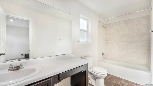 a bathroom with a sink a toilet a mirror and shower