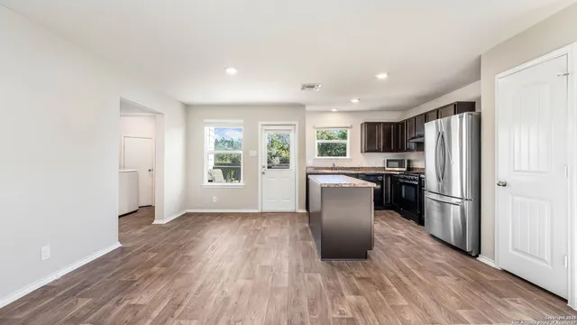 a kitchen with a refrigerator and wooden floor