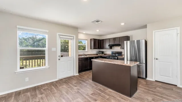 a kitchen with stainless steel appliances granite countertop a refrigerator and a stove top oven