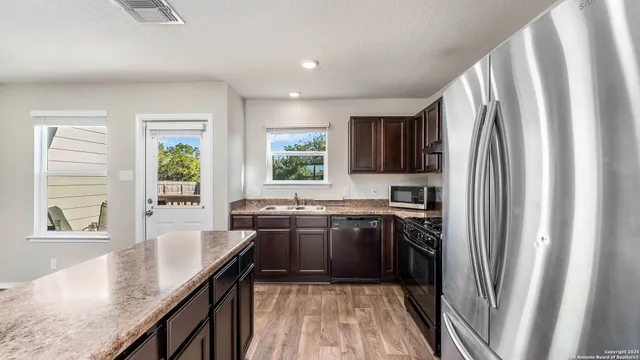 a kitchen with stainless steel appliances granite countertop refrigerator a sink a stove a washer dryer and wooden cabinets