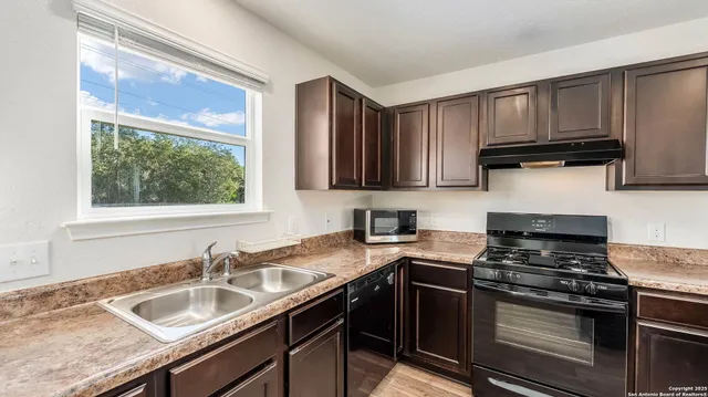 a kitchen with granite countertop a sink stove and cabinets