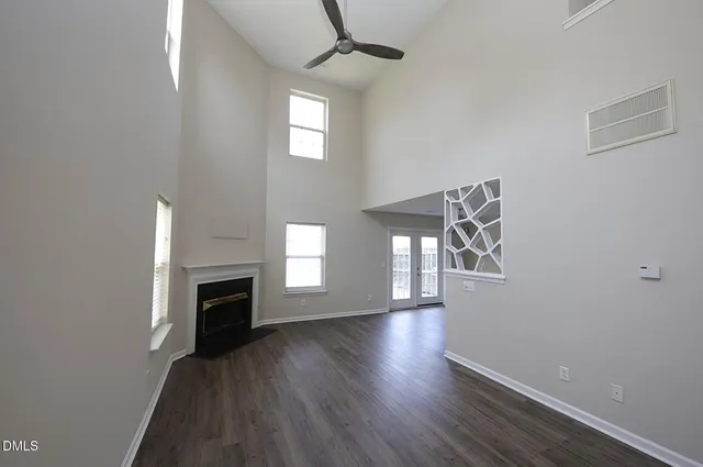 an empty room with wooden floor a fireplace and windows