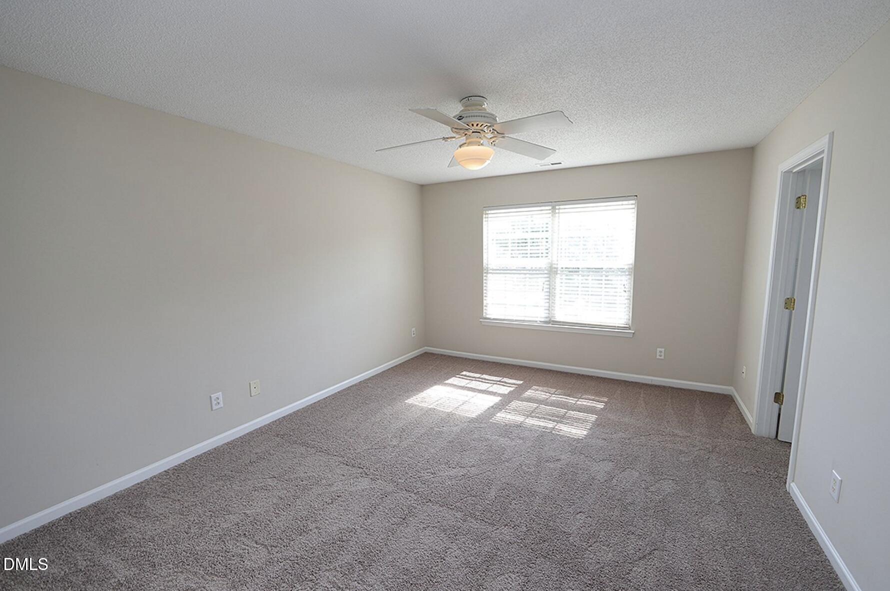 9904 Treymore Drive Raleigh, NC 27617 - Photo 6 of 14 an empty room with a window and a ceiling fan