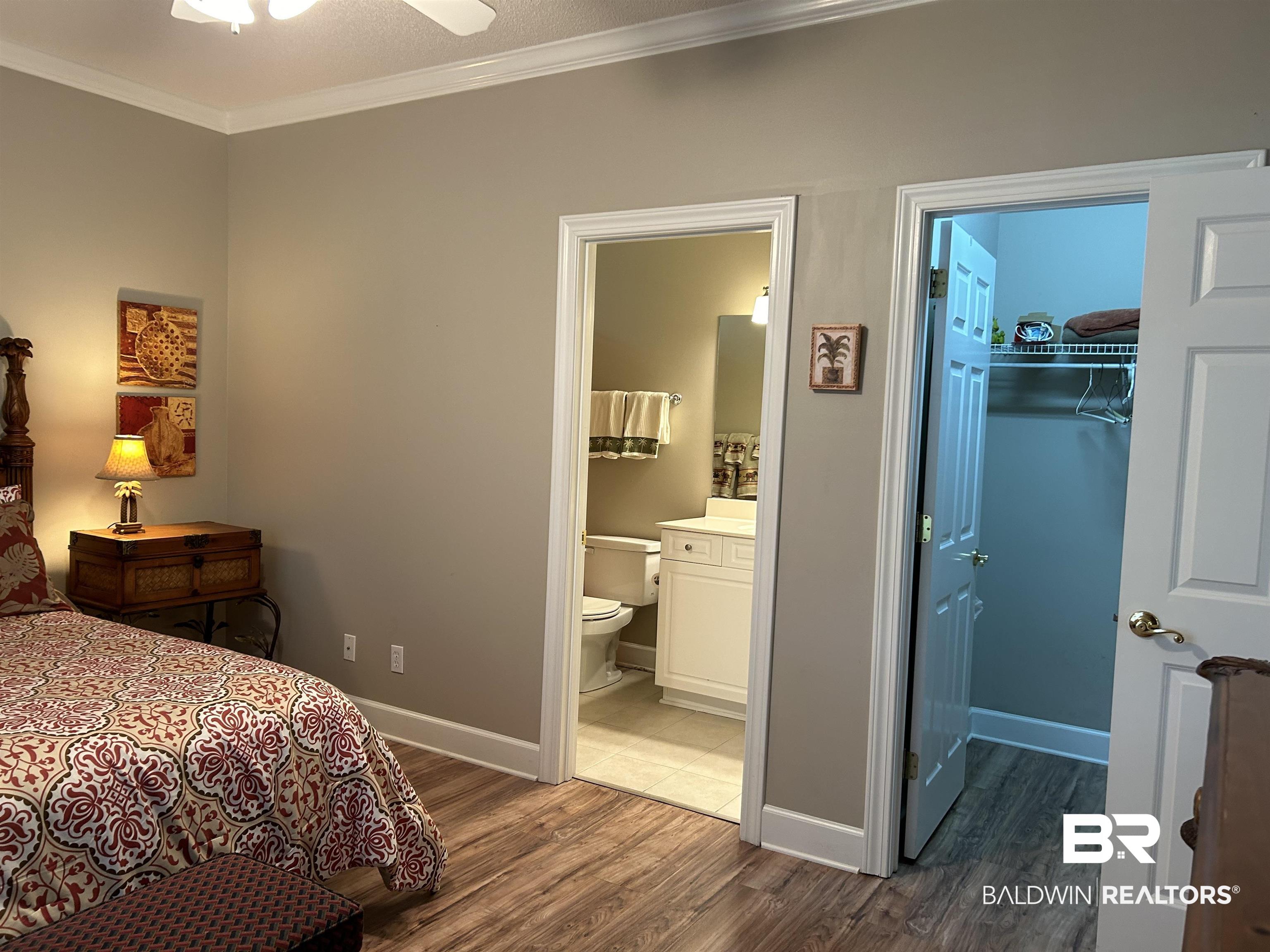 430 West Fort Morgan Road, Unit 404 Gulf Shores, AL 36542 - Photo 18 of 31 Bedroom featuring crown molding, a spacious closet, ceiling fan, dark hardwood / wood-style floors, and ensuite bath