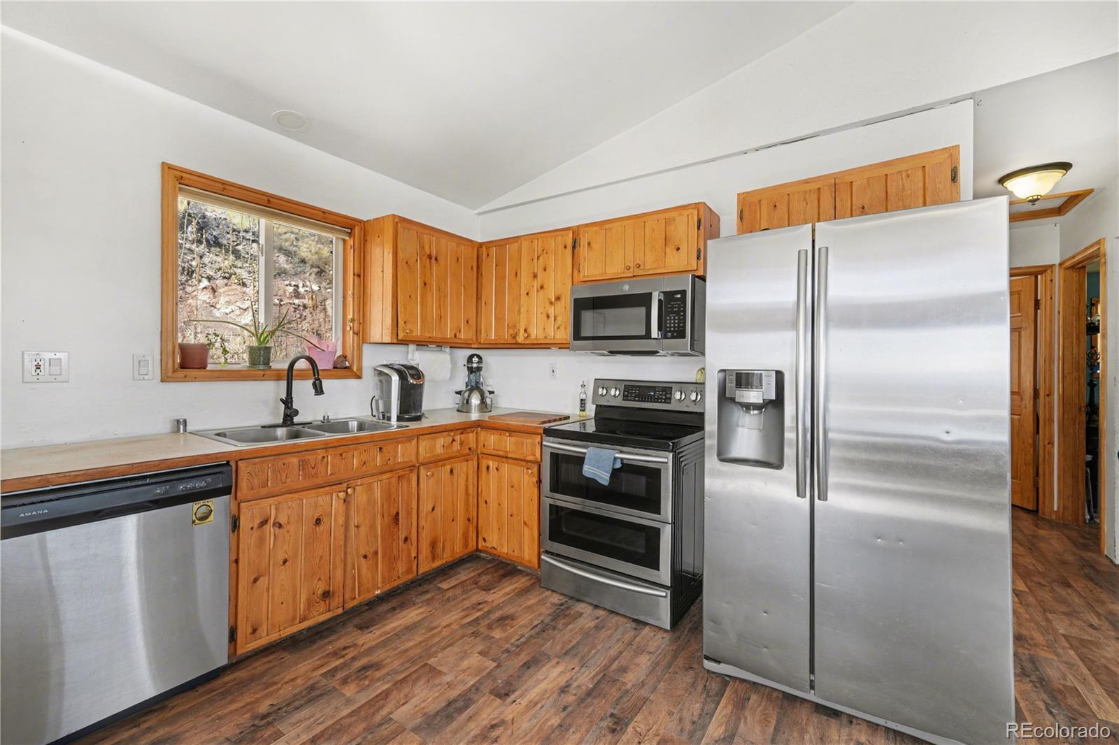 319 Springmeadow Way Red Feather Lakes, CO 80545 - Photo 4 of 30 a kitchen with stainless steel appliances granite countertop a refrigerator a sink dishwasher a stove with wooden cabinets and floor
