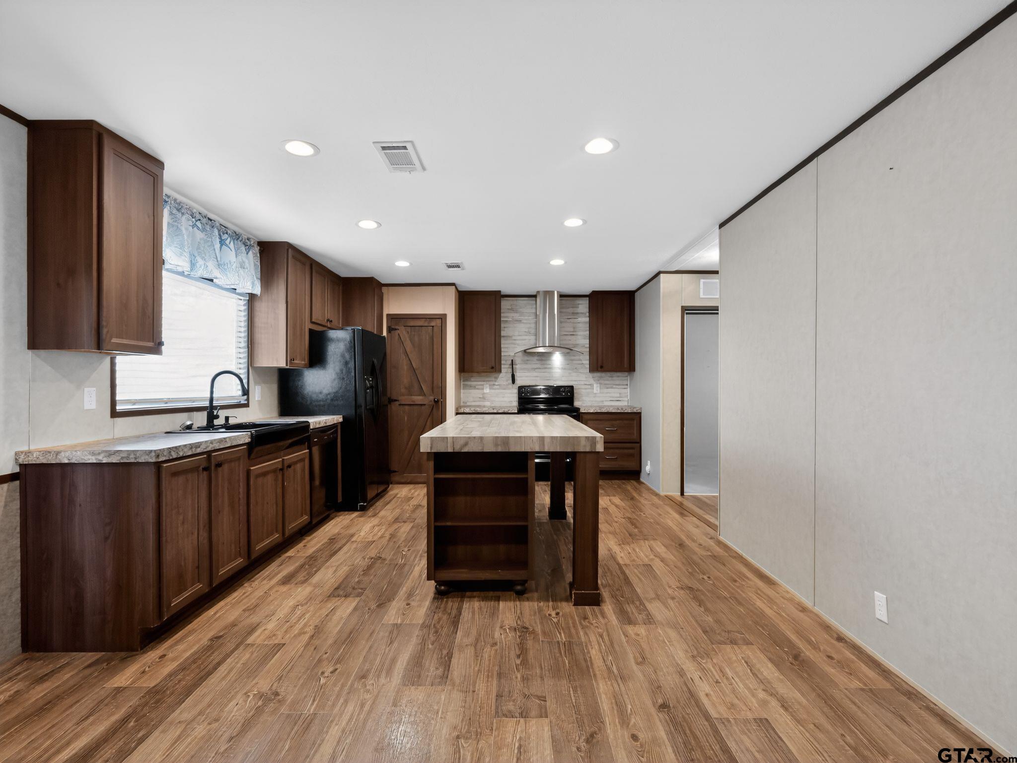 149 Running Bear Quitman, TX 75783 - Photo 8 of 31 a kitchen with stainless steel appliances a dining table chairs stove refrigerator and cabinets