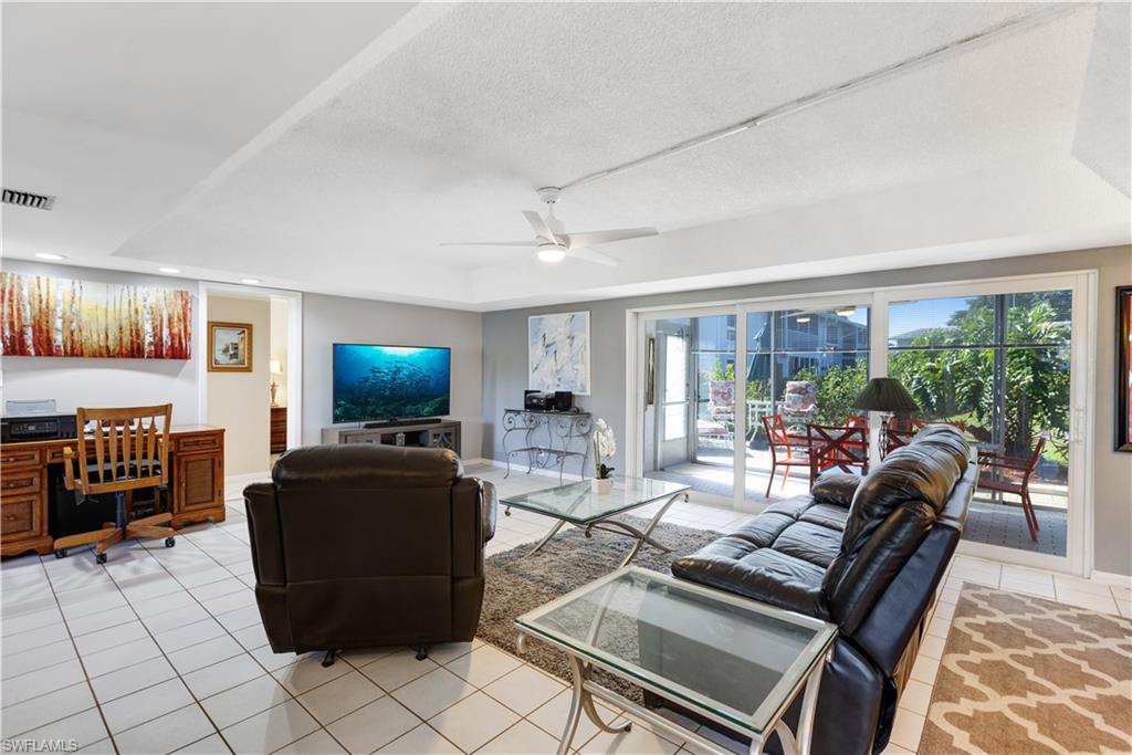 154 Penny Lane, Unit 7 Naples, FL 34112 - Photo 26 of 50 a living room with furniture a flat screen tv and floor to ceiling window