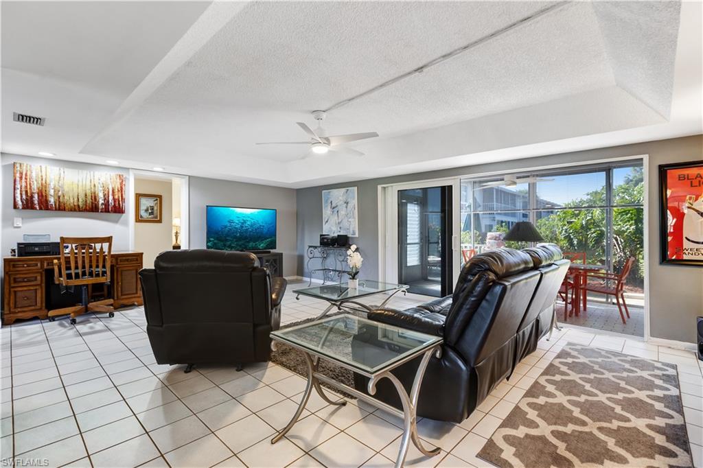 154 Penny Lane, Unit 7 Naples, FL 34112 - Photo 31 of 50 a living room with furniture a flat screen tv and a floor to ceiling window