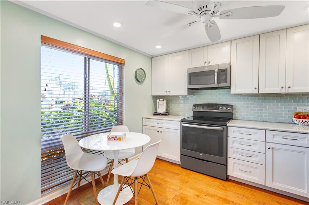154 Penny Lane, Unit 7 Naples, FL 34112 - Photo 7 of 50 a kitchen with stainless steel appliances granite countertop a kitchen island hardwood floor sink stove dining table and chairs