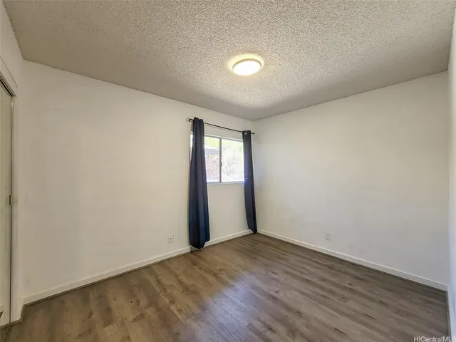 a view of an empty room with wooden floor and window