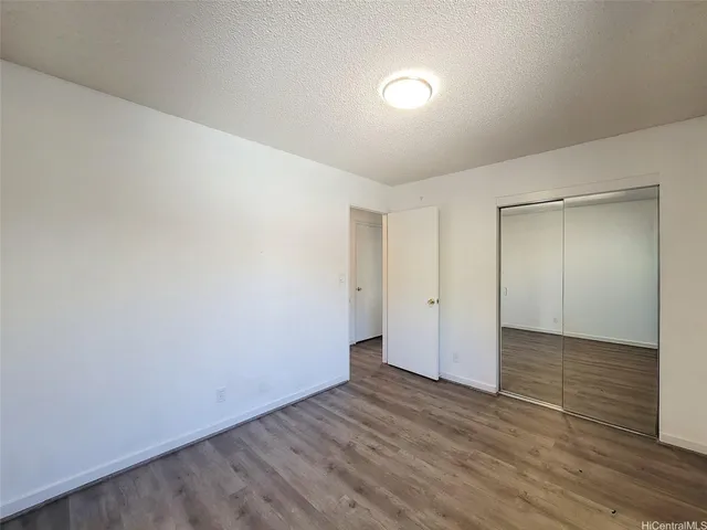 a view of an empty room with wooden floor and closet