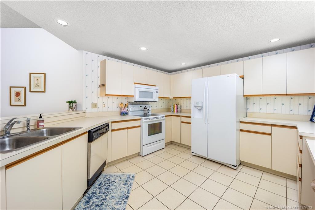 6101 Southeast Landing Way, Unit 5 Stuart, FL 34997 - Photo 6 of 13 a kitchen with white cabinets a sink and white appliances