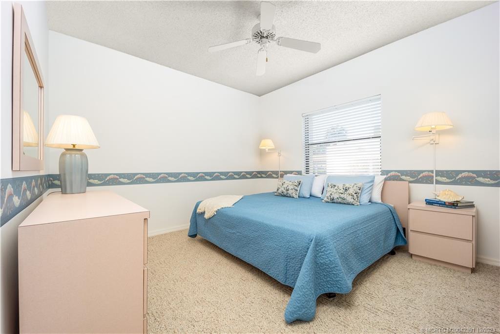 6101 Southeast Landing Way, Unit 5 Stuart, FL 34997 - Photo 9 of 13 a spacious bedroom with a bed and a chandelier