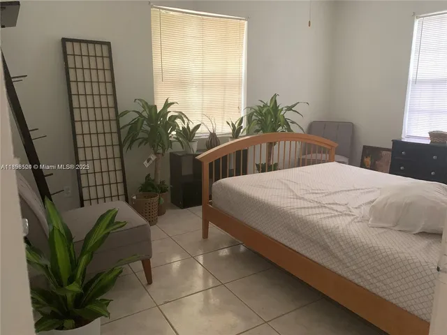a bedroom with a bed table flowerpot and a potted plant