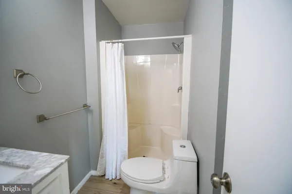 a bathroom with a granite countertop bathtub shower sink vanity and toilet
