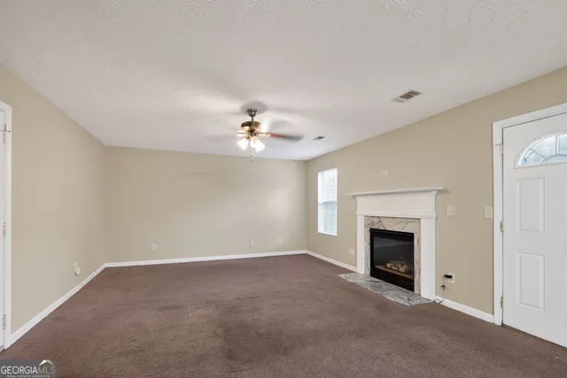 an empty room with chandelier fan and fireplace