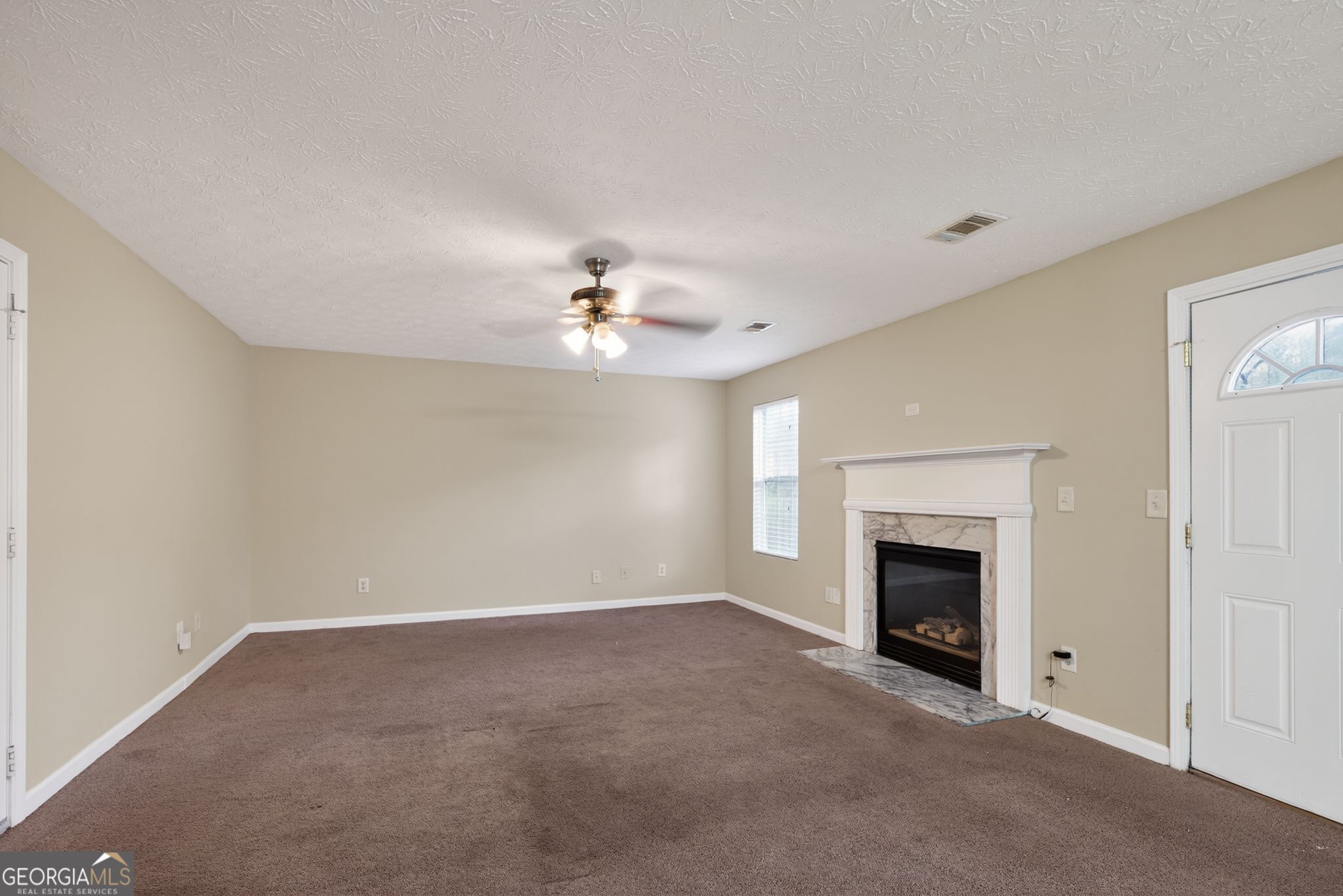 6463 Castle Ct Way Lithonia, GA 30058 - Photo 11 of 35 an empty room with chandelier fan and fireplace