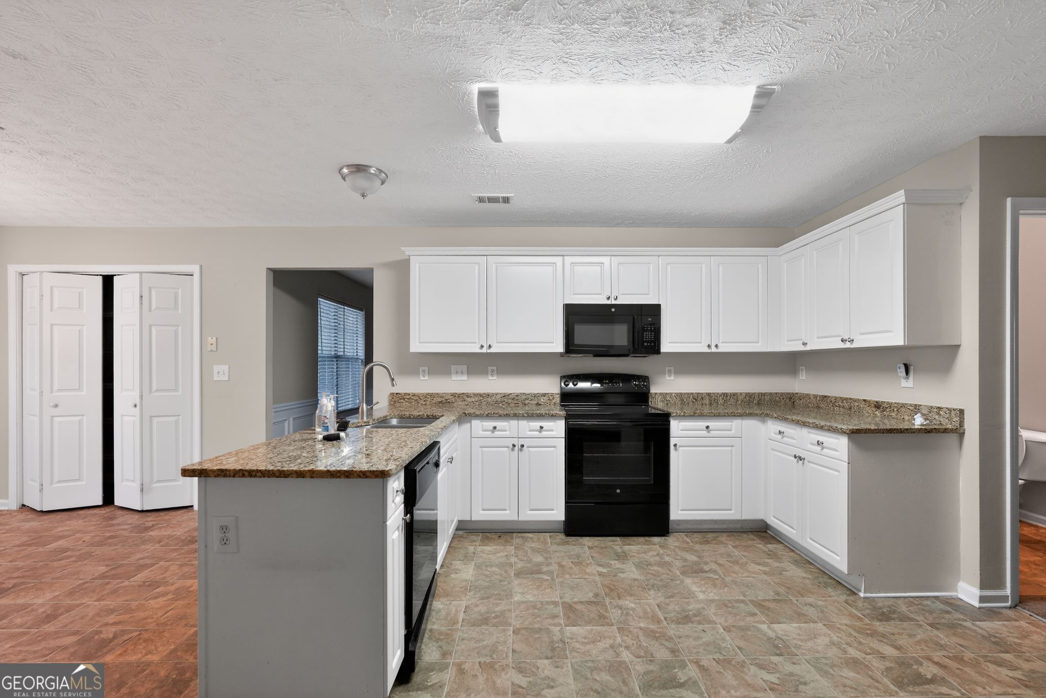 6463 Castle Ct Way Lithonia, GA 30058 - Photo 15 of 35 a kitchen with stainless steel appliances granite countertop a stove sink and cabinets