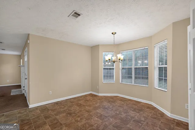 an empty room with windows and chandelier fan