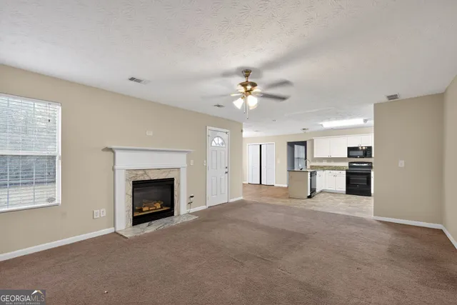 a view of an empty room with chandelier and fireplace