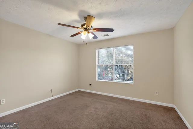 an empty room with windows and fan
