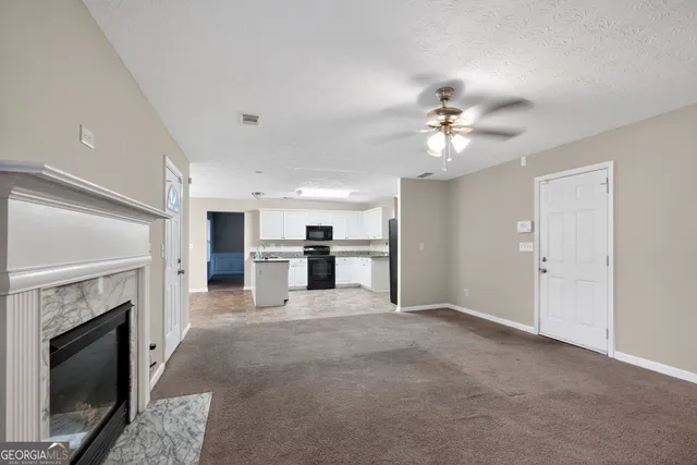 a view of kitchen with fireplace ceiling fan and refrigerator