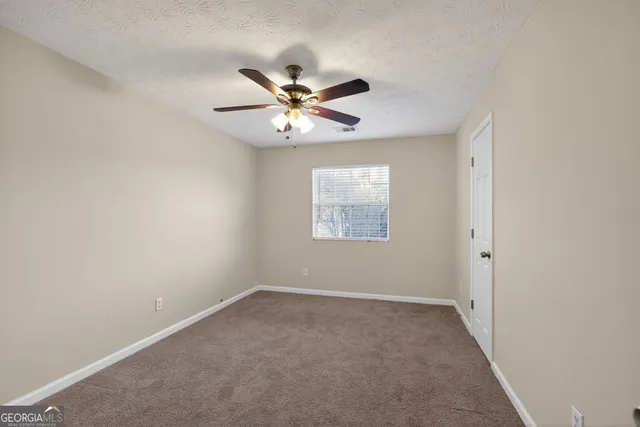 an empty room with a window and a fan