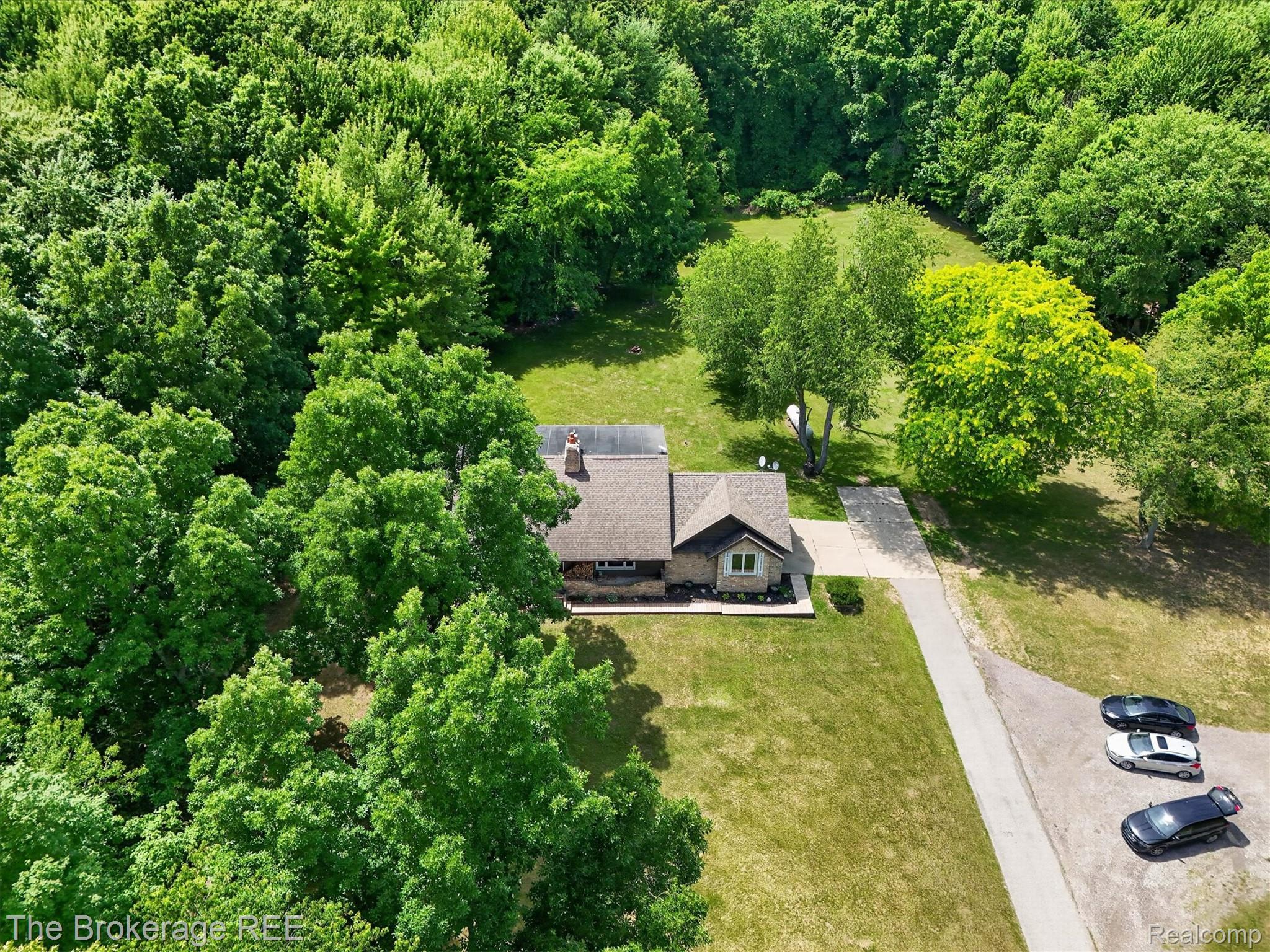 13269 North Genesee Road Clio, MI 48420 - Photo 51 of 67 Expansive wooded lot featuring a single-story residence with a brown shingle roof, light-colored siding, and a prominent chimney