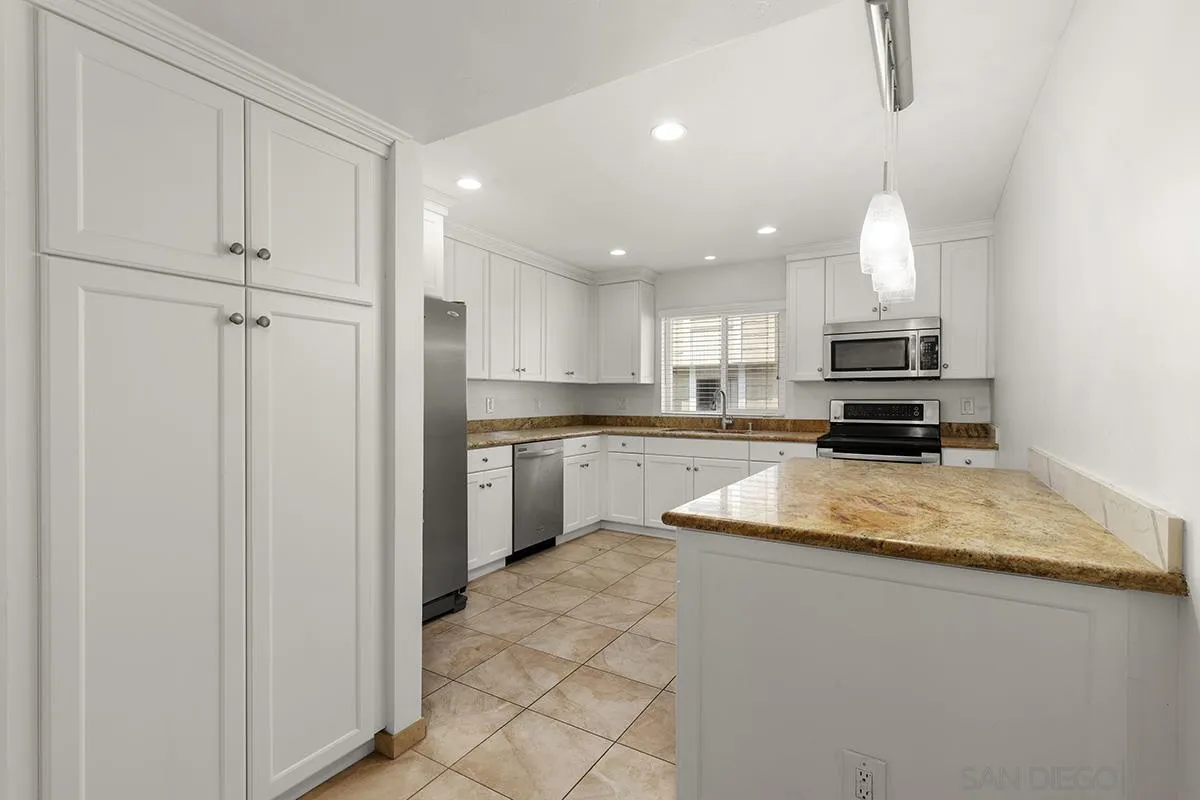 4028 Mahaila Avenue, Unit C San Diego, CA 92122 - Photo 13 of 34 a kitchen with kitchen island granite countertop a sink stainless steel appliances and cabinets