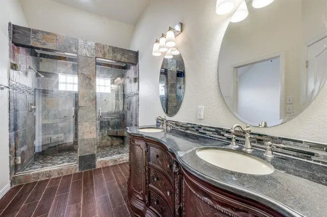 a bathroom with a double vanity sink mirror and shower