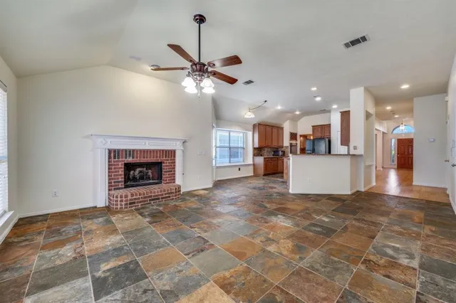 a view of a livingroom with a fireplace a ceiling fan and kitchen view