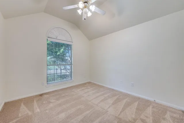 a view of an empty room with a chandelier fan