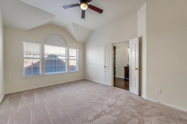 an empty room with chandelier fan and windows