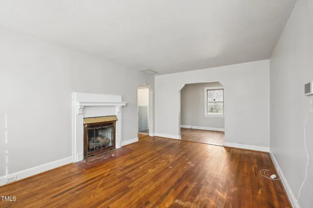 a view of empty room with wooden floor and fireplace