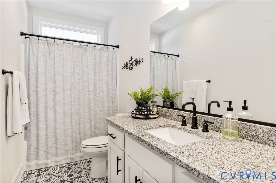8614 Terroir Lane New Kent, VA 23124 - Photo 25 of 42 a bathroom with a granite countertop sink a toilet and a mirror