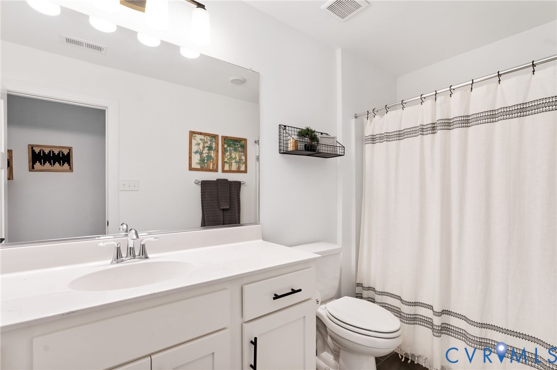 8614 Terroir Lane New Kent, VA 23124 - Photo 29 of 42 a bathroom with a sink a toilet a mirror and shower curtain