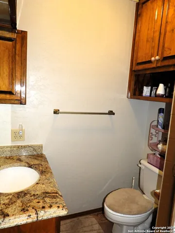 a bathroom with a granite countertop toilet and a sink
