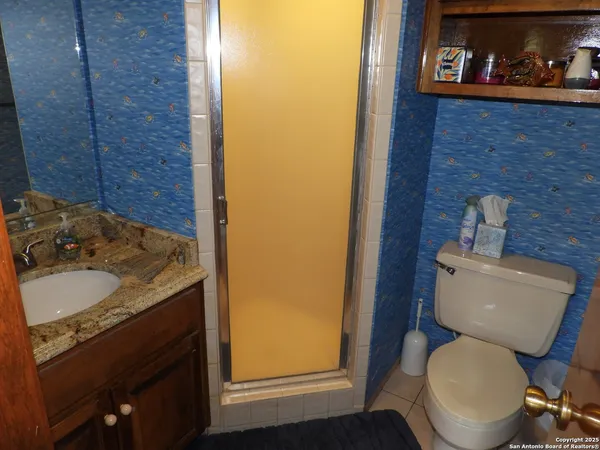 a bathroom with a granite countertop toilet and a sink