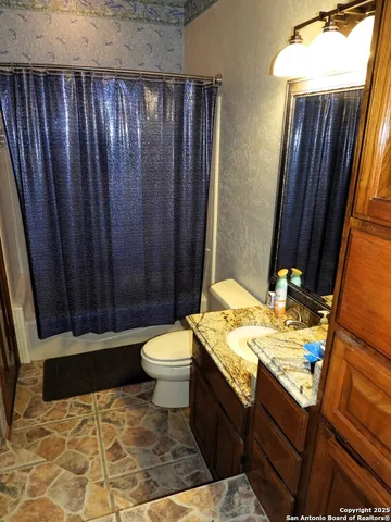 a bathroom with a sink a toilet and shower curtain